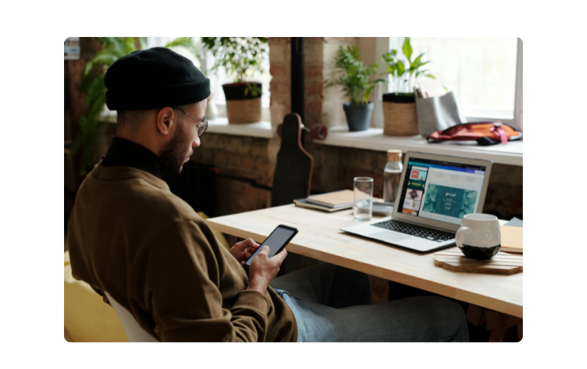 Man working on his online business from home, using a laptop and smartphone, showcasing modern side hustles in 2025.